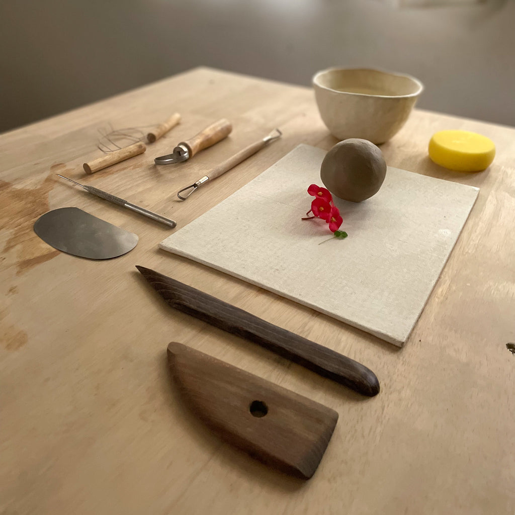 Handbuilding setup with clay, pottery tools and a canvas board