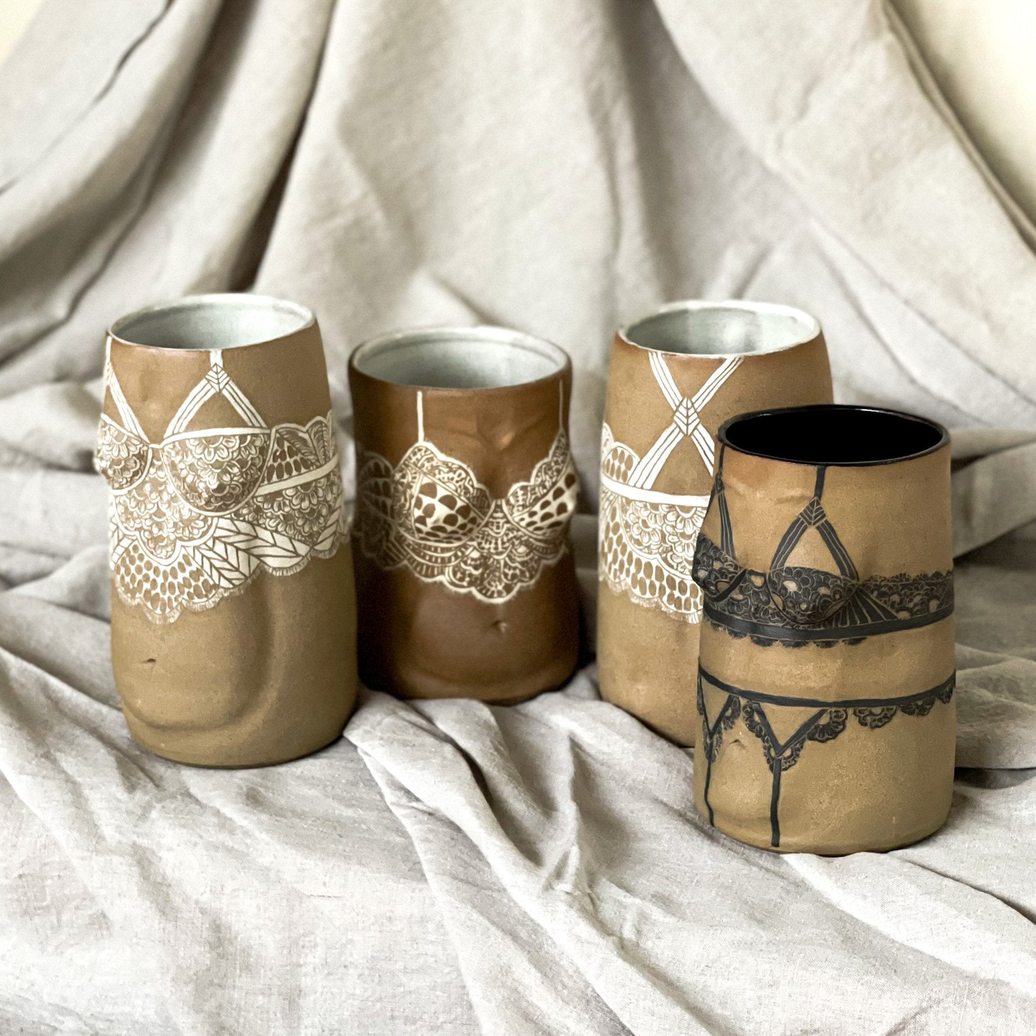 Hero shot of four vases from Déesses de la nuit Collection. Brown stoneware vases in the shape of the female form. With sgraffito lacework carving in white and black slips.