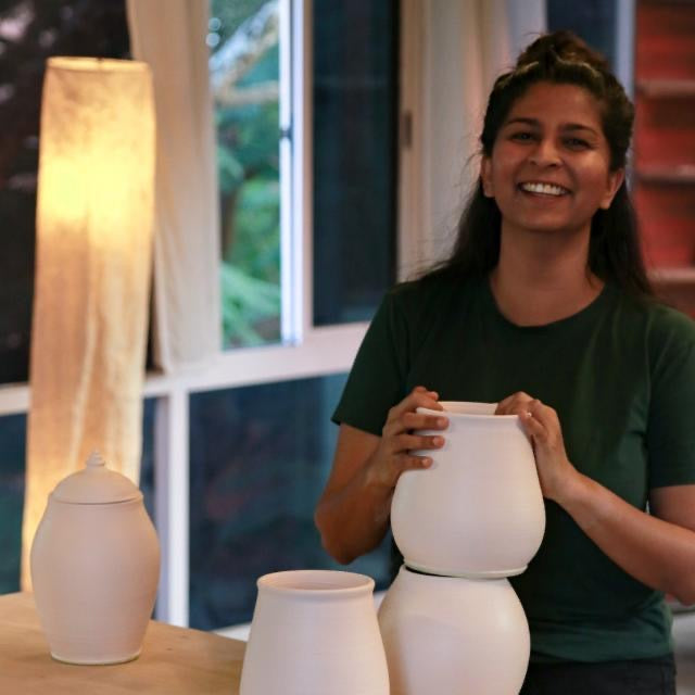 Artist portrait of Gauri Oak with her pots in a studio setting